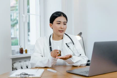 Doctor in lab coat speaking to a patient online