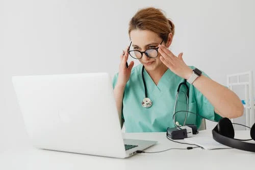 Doctor in teal scrub speaking to a patient online