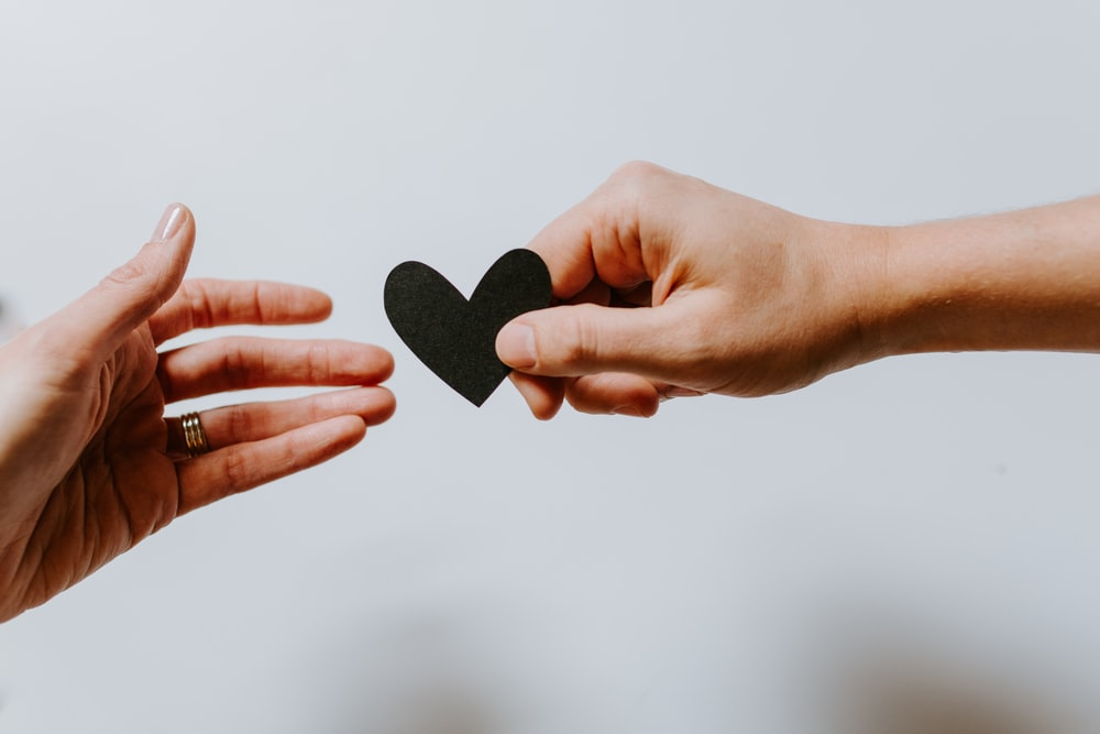 a person reaching black heart cutout paper