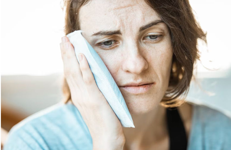 Woman using cold compress for toothache.