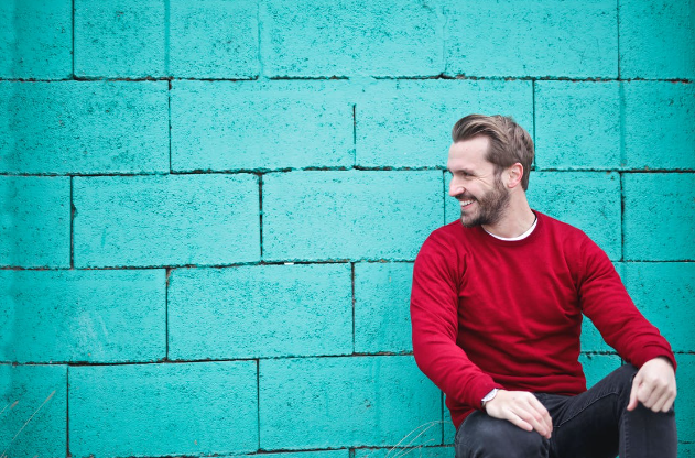 Man sitting against blue wall.