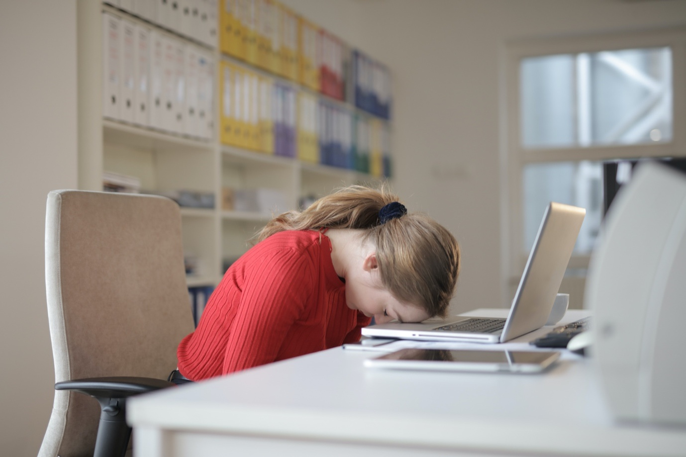 A person with their head down in front of a laptop